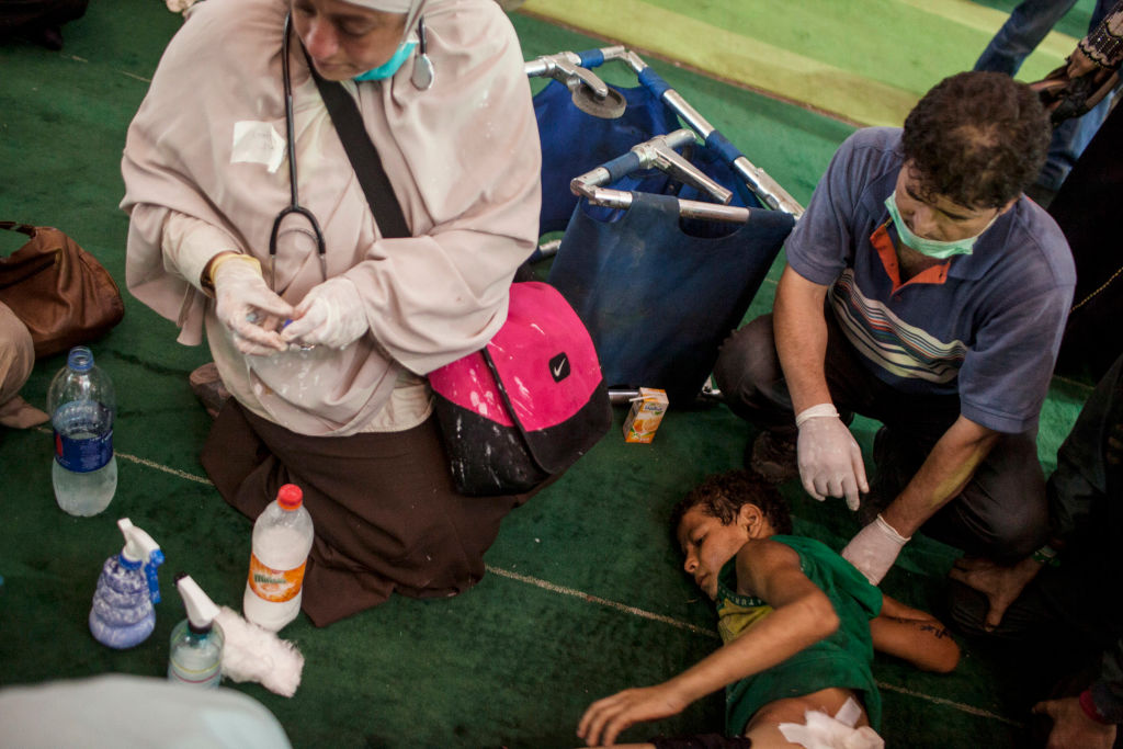 Medics treat a boy wounded by Egyptian security forces on August 16, 2013, two days after the mass murder of protestors at Rab'a Square. (Getty)