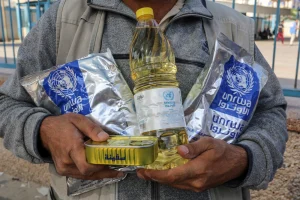 A Palestinian refugee carries cooking supplies provided by UNRWA at a refugee camp in Khan Younis, Gaza. (Shutterstock)