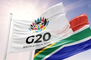 A G20 and South African flag fly together in the wind.